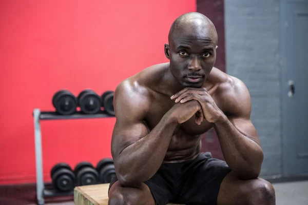 Young Bodybuilder sitting on a wooden Block — Stock Photo, Image