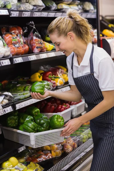 Lächelnde blonde Arbeiterin, die ein Gemüse nimmt — Stockfoto