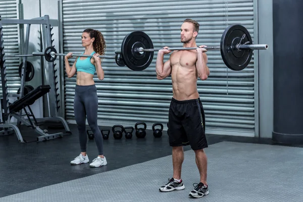 Muscular couple lifting weight together — Stock Photo, Image