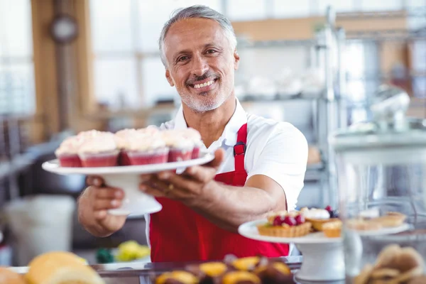 Barista segurando prato de cupcakes — Fotografia de Stock