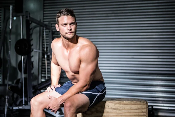 Focused muscular man sitting on a box — Stock Photo, Image