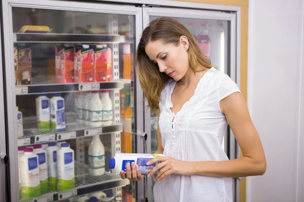 Hübsche Frau schaut auf Flasche Milch — Stockfoto