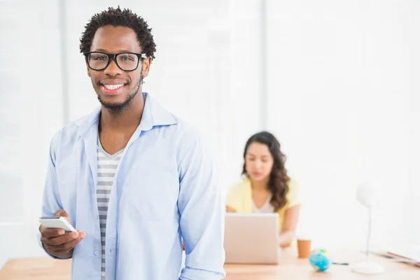 Sorrindo homem posando na frente de seu colega com smartphone — Fotografia de Stock