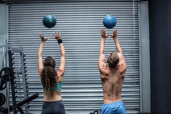 Musculosa pareja lanzando pelota en el aire — Foto de Stock