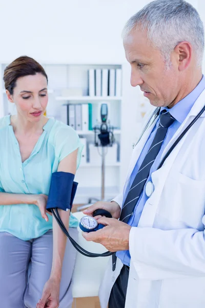 Médico verificando a pressão arterial de uma jovem mulher — Fotografia de Stock