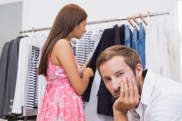 Gelangweilter Mann wartet Frau in Boutique — Stockfoto