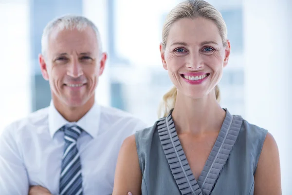 Two business people smiling at the camera in the office — Stock Photo, Image