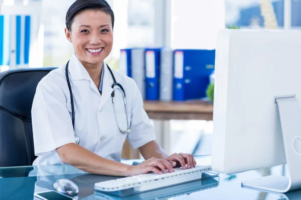 Médico feliz usando seu computador e olhando para a câmera — Fotografia de Stock