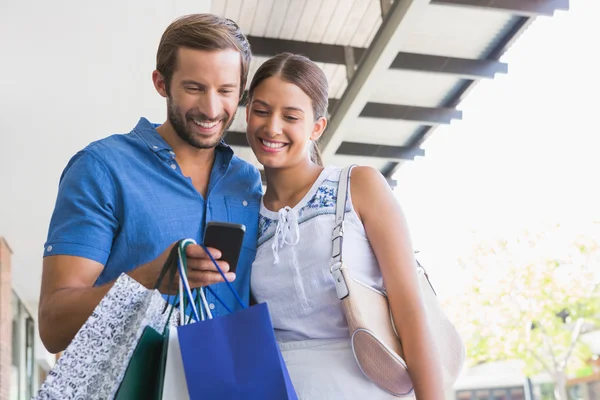 Casal olhando para o telefone depois de fazer compras — Fotografia de Stock