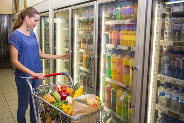 Jolie femme regardant la caméra et prenant le produit sur le réfrigérateur — Photo