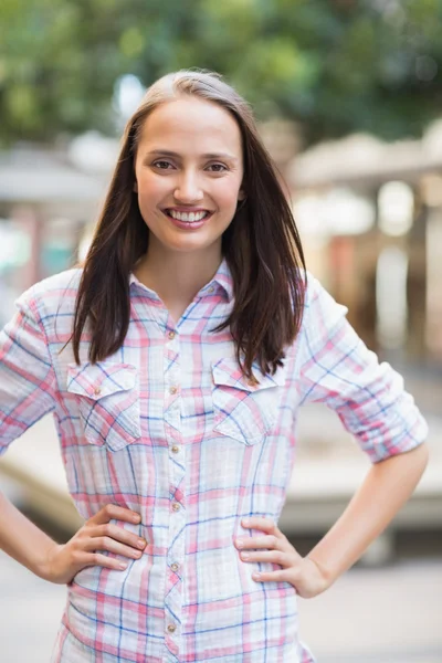 Bonita morena con las manos en las caderas sonriendo a la cámara — Foto de Stock