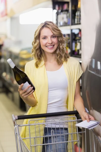 Mulher segurando garrafa de vinho no supermercado — Fotografia de Stock