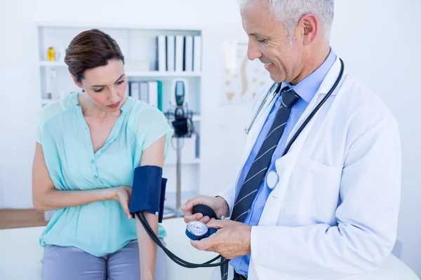 Doctor checking blood pressure of a young woman — Stock Photo, Image