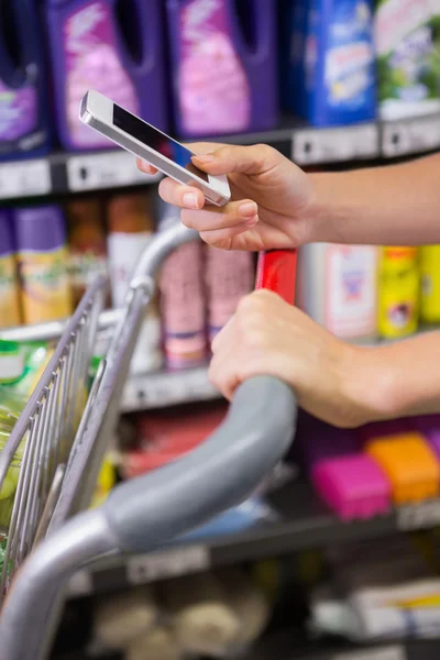 Vrouw kopen producten en gebruikend zijn smartphone — Stockfoto