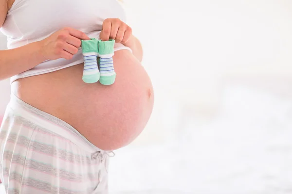 Zwangere vrouw met baby schoenen over hobbel — Stockfoto