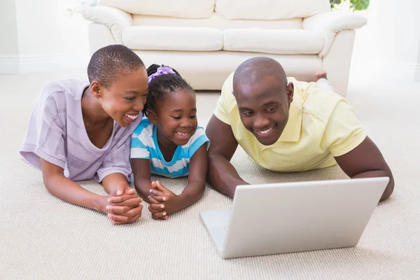 Felice coppia sorridente utilizzando il computer portatile con la figlia — Foto Stock