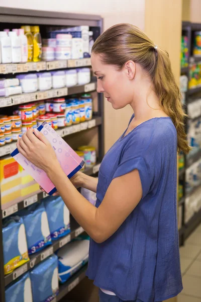 Mujer bonita recogiendo caja en estante —  Fotos de Stock