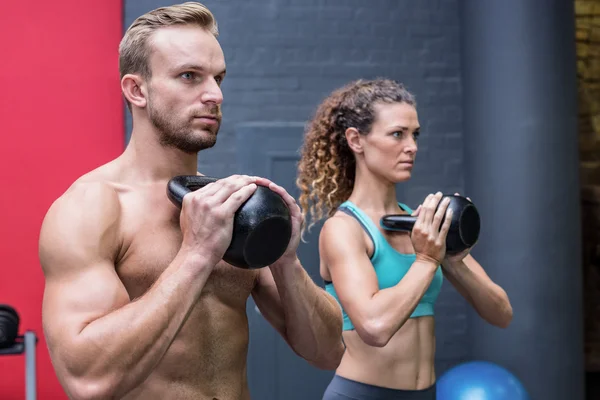 Muskulöses Paar, das mit Kettlebells trainiert — Stockfoto