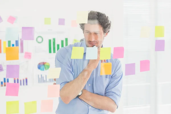 Creative businessman looking at post-it — Stockfoto