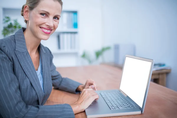 Smiling blonde businesswoman working on laptop — Stock Photo, Image