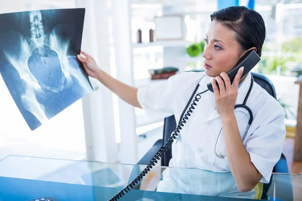 Доктор смотрит на рентген во время телефонного звонка — стоковое фото