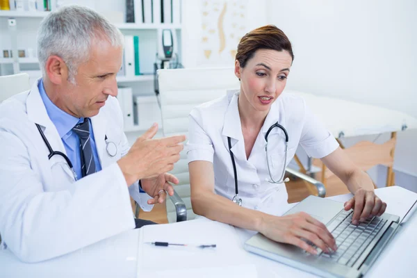 Colegas médicos concentrados discutiendo y trabajando con lapt — Foto de Stock