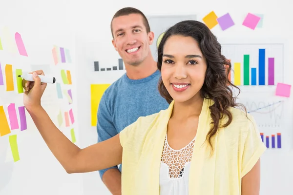 Portrait of smiling coworkers writing on sticky notes — Stock Photo, Image