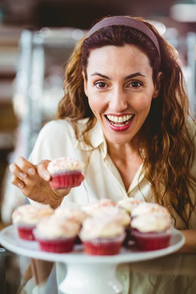 Dość brunetka uśmiecha się do kamery i trzyma tort — Zdjęcie stockowe