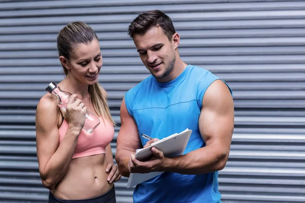 Mujer muscular viendo sus resultados en el portapapeles —  Fotos de Stock