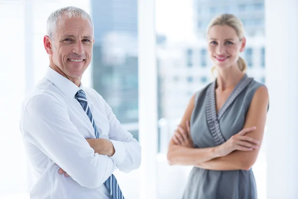Twee mensen uit het bedrijfsleven glimlachend in de camera in het kantoor — Stockfoto