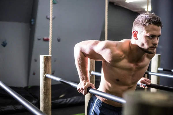 Мускулистый мужчина тренируется на параллельных брусьях — стоковое фото