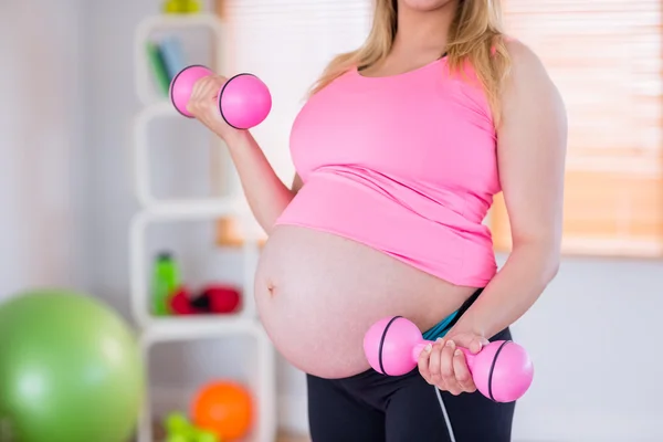 Une femme enceinte tenant des haltères — Photo