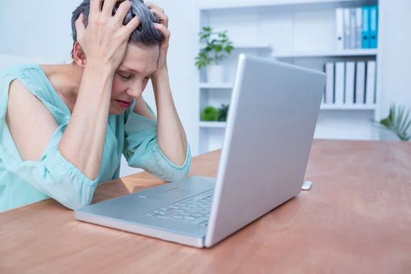 Empresária perturbada franzindo a testa em seu laptop — Fotografia de Stock
