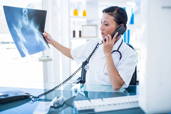 Médico buscando rayos X mientras tiene una llamada telefónica — Foto de Stock