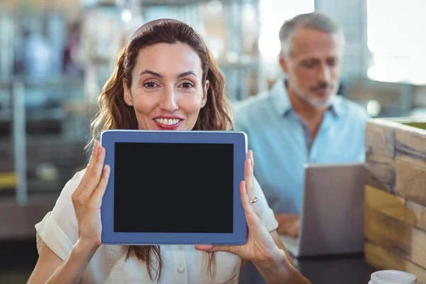 Morena bonita olhando para a câmera e mostrando tablet — Fotografia de Stock