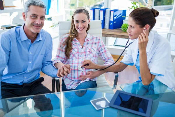 Smiling pregnant woman and her husband with doctor — Stock Photo, Image