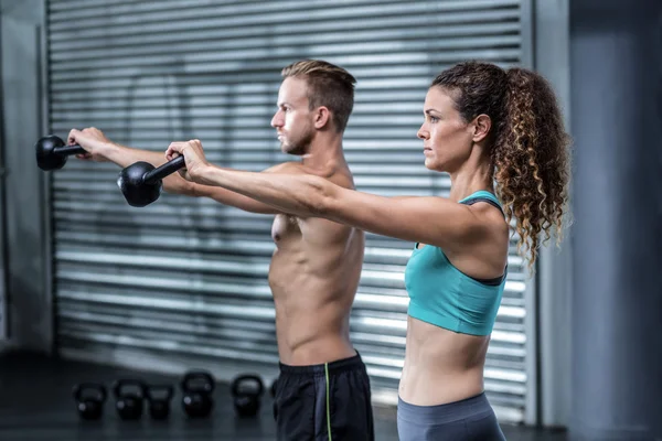 Una coppia muscolare che solleva kettlebells — Foto Stock