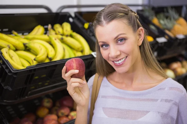 Hübsche blonde Frau zeigt einen roten Apfel — Stockfoto