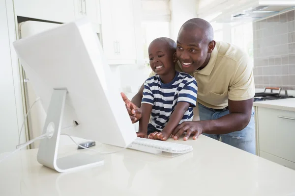 Feliz padre sonriente con su hijo usando la computadora —  Fotos de Stock