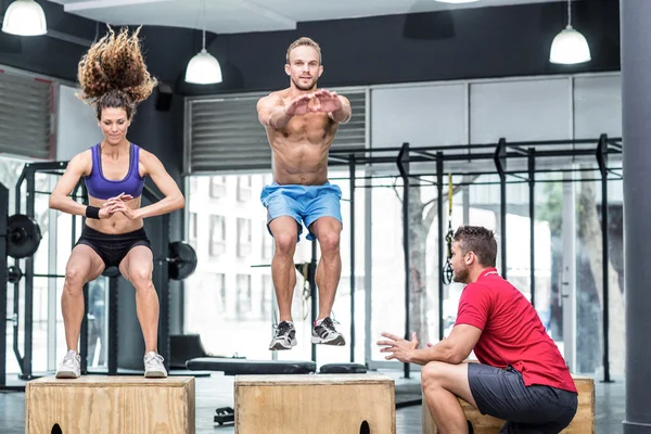 Atletas musculares fazendo agachamentos salto — Fotografia de Stock