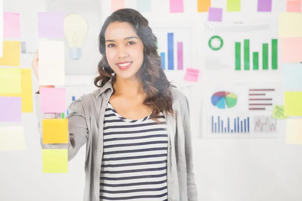 Pretty designer looking at post its on window — Stock Photo, Image