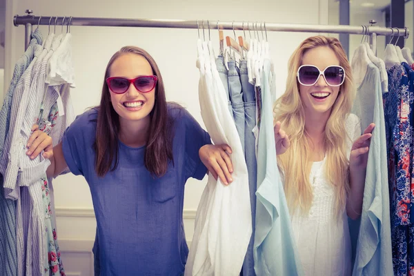 Amigos felizes olhando através do rack de roupas — Fotografia de Stock