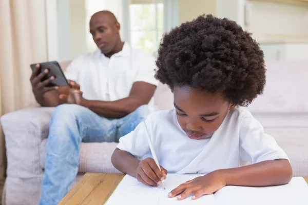 Een kleine jongen schrijven op Kladblok — Stockfoto