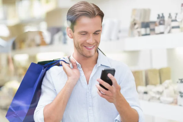 En lycklig leende man tittar på telefonen — Stockfoto