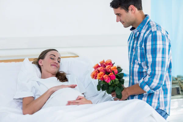 Man erbjuder blommor till gravid kvinna — Stockfoto