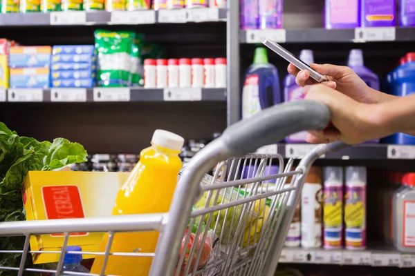 Frau kauft Produkte und benutzt sein Smartphone — Stockfoto