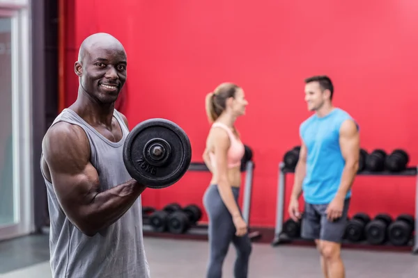 Sonriente musculoso levantando una mancuerna — Foto de Stock