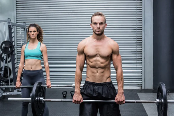 Muscular couple lifting weight together — Stock Photo, Image