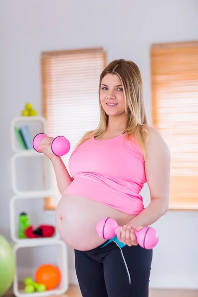 A pregnant woman holding dumbbells — Stock Photo, Image