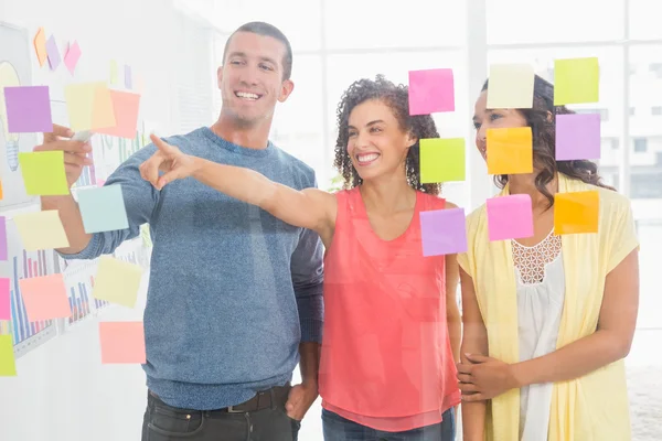 Smiling coworkers pointing sticky notes — Stock Photo, Image